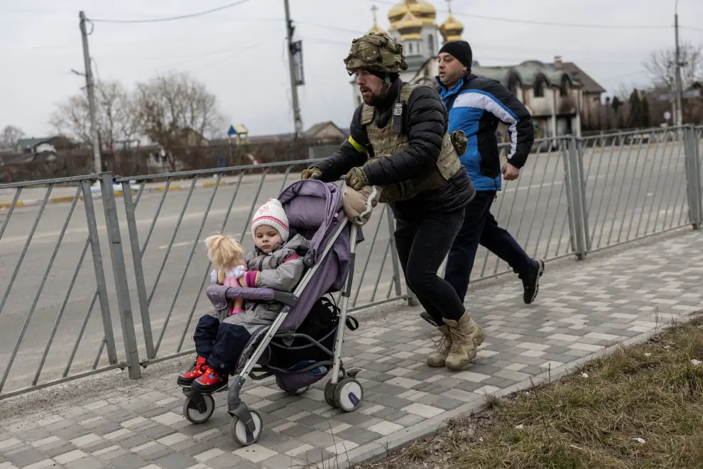 A man takes a pause as he evacuates from the town, on the only escape route used by locals after days of heavy shelling, while Russian troops advance towards the capital, in Irpin, near Kyiv, Ukraine March 7, 2022. REUTERS/Carlos Barria UKRAINE-CRISIS/IRPIN