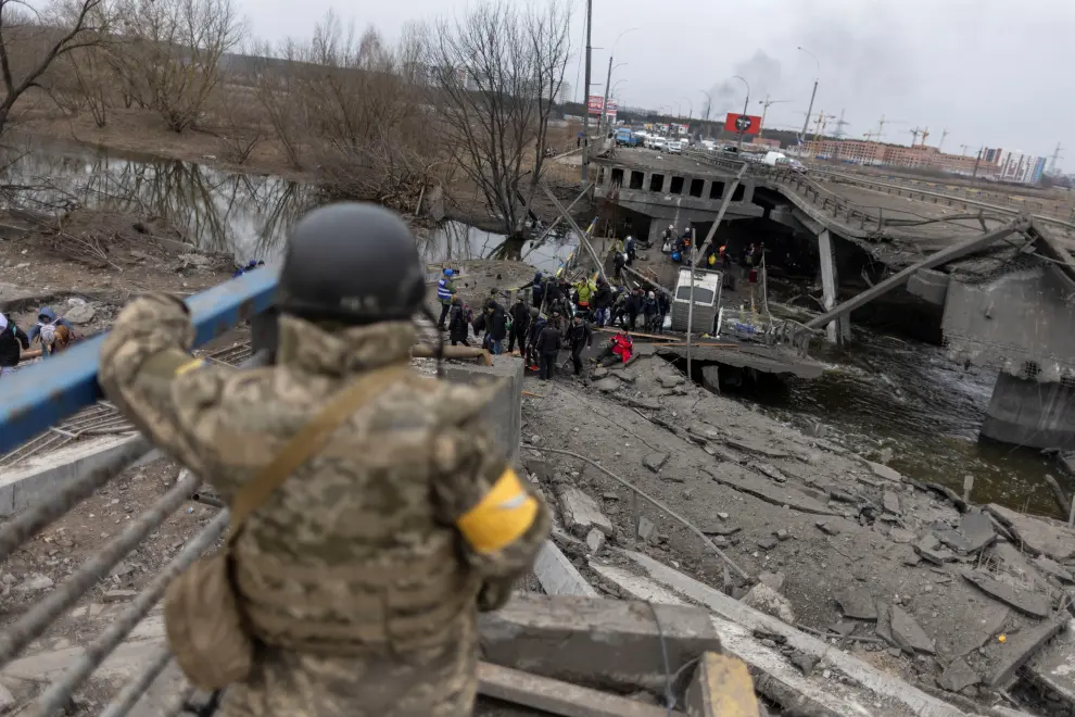 Local residents cross a destroyed bridge as they evacuate from the town of Irpin, after days of heavy shelling on the only escape route used by locals, while Russian troops advance towards the capital, in Irpin, near Kyiv, Ukraine March 7, 2022. REUTERS/Carlos Barria UKRAINE-CRISIS/IRPIN