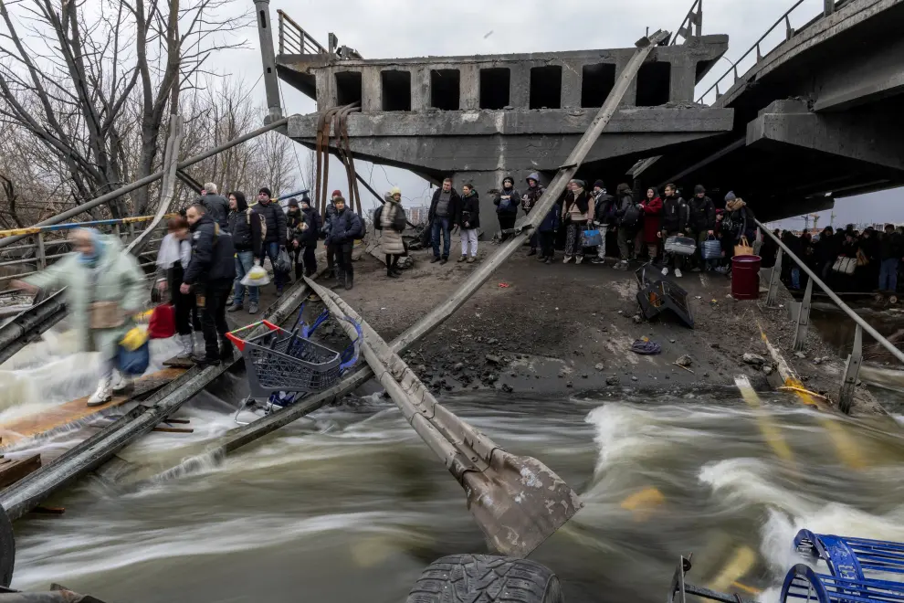 A person walks with a dog as local residents cross a destroyed bridge as they evacuate from the town of Irpin, after days of heavy shelling on the only escape route used by locals, while Russian troops advance towards the capital, in Irpin, near Kyiv, Ukraine March 7, 2022. REUTERS/Carlos Barria UKRAINE-CRISIS/IRPIN