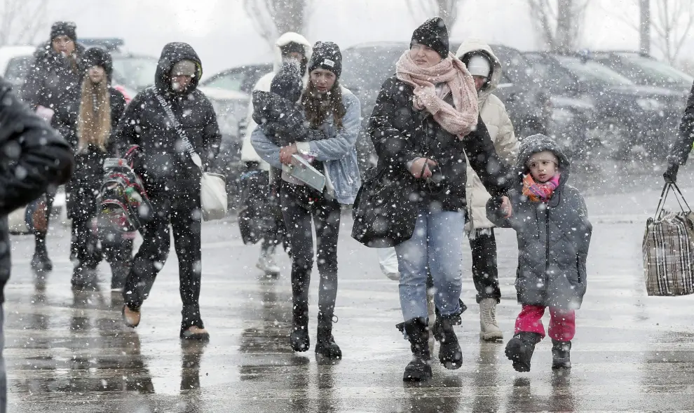 Refugiados ucranianos reciben flores a su llegada bajo la nieve a la frontera con Rumanía.