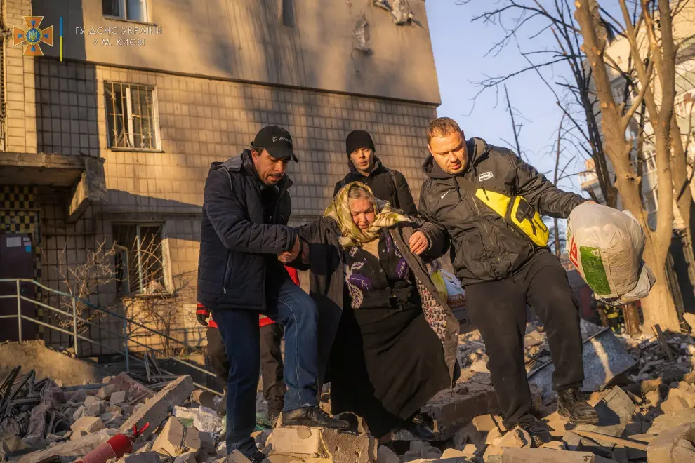Rescuers help a woman evacuate a residential building damaged by shelling, as Russia's attack on Ukraine continues, in Kyiv, Ukraine, in this handout picture released March 16, 2022.  Press service of the State Emergency Service of Ukraine/Handout via REUTERS ATTENTION EDITORS - THIS IMAGE HAS BEEN SUPPLIED BY A THIRD PARTY. UKRAINE-CRISIS/KYIV