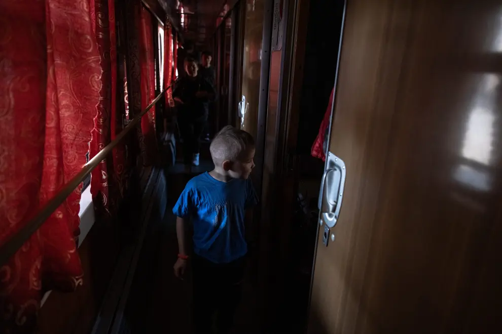 Zaporizhzhia (Ukraine), 26/03/2022.- An orphan child who fled from the occupied by the Russian army Ukrainian town of Polohy, waits in an evacuation train before leaving to the western part of Ukraine, at the railway station in Zaporizhzhia, southeastern Ukraine, 26 March 2022. Around 30 orphan children from an orphanage in the Polohy town, Zaporizhzhia region, following the fightings and occupation of the town by the Russian military, fled with their teachers to the city of Zaporizhzhia. From there they went to the western part of Ukraine, where they hope to find a safe place far from the active war zones. (Rusia, Ucrania) EFE/EPA/ROMAN PILIPEY ATTENTION: This Image is part of a PHOTO SET
 PHOTO SET UKRAINE RUSSIA WAR EVACUATION OF ORPHAN CHILDREN