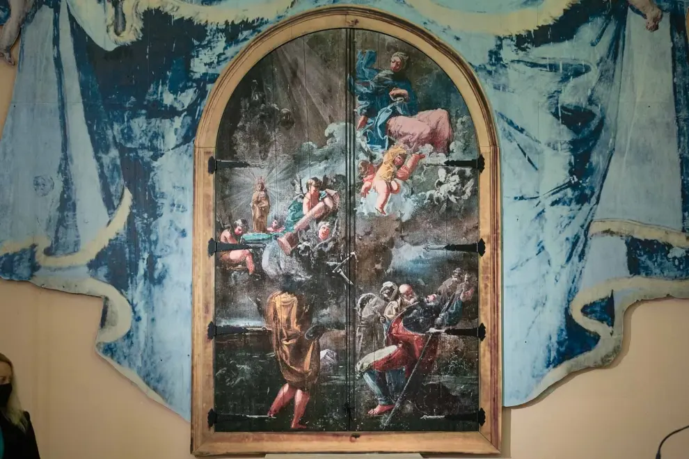 Las puertas del armario reproducen, en su exterior, la 'Venida de la Virgen del Pilar a Zaragoza'. En el interior, la Virgen del Carmen con el Niño y San Francisco de Paula
