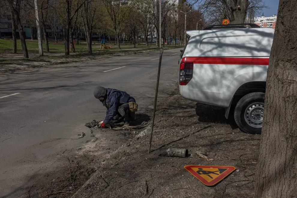 Kharkiv (Ukraine), 15/04/2022.- Oleksandr Gumenchak (C) and Vladyslav Shapoval (R), deminers of the State Emergency Service of Ukraine remove a metal piece of Grad rocket that is stuck on a road after the Russian attack, on the outskirts of Kharkiv, near the frontline, northeast Ukraine, 15 April 2022. Every day the group of deminers checks dozens of places looking for different explosive items in Kharkiv. Ukraine's second-largest city and its surrounding area have been heavily shelled by Russian forces, with many civilians killed, since Russia's military invasion of Ukraine began on 24 February 2022. (Atentado, Rusia, Ucrania) EFE/EPA/ROMAN PILIPEY ATTENTION: This Image is part of a PHOTO SET
 UKRAINE RUSSIA CONFLICT PHOTO SET DEMINING