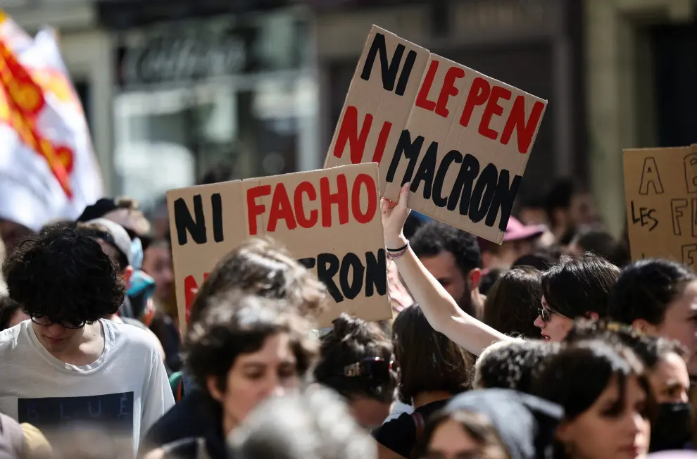 A member of the Yellow Vests movement holds a placard with the words "Pest" and "Cholera" and with pictures of French President Emmanuel Macron and far-right presidential candidate Marine Le Pen, during a demonstration against far-right, racism and fascism ahead of the second round of the 2022 presidential election, in Paris, France, April 16, 2022. REUTERS/Sarah Meyssonnier FRANCE-ELECTION/PROTEST