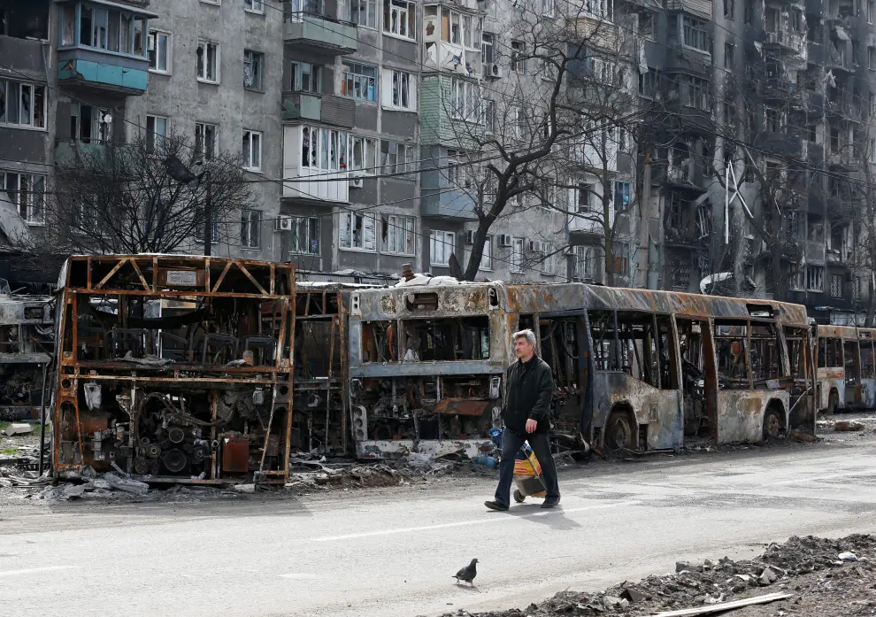 A local resident pulls a cart with humanitarian aid past an apartment building damaged during Ukraine-Russia conflict in the southern port city of Mariupol, Ukraine April 19, 2022. REUTERS/Alexander Ermochenko UKRAINE-CRISIS/MARIUPOL