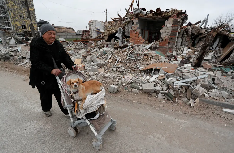 A local resident puses a cart with belongings past a building destroyed during Ukraine-Russia conflict in the southern port city of Mariupol, Ukraine April 19, 2022. REUTERS/Alexander Ermochenko UKRAINE-CRISIS/MARIUPOL