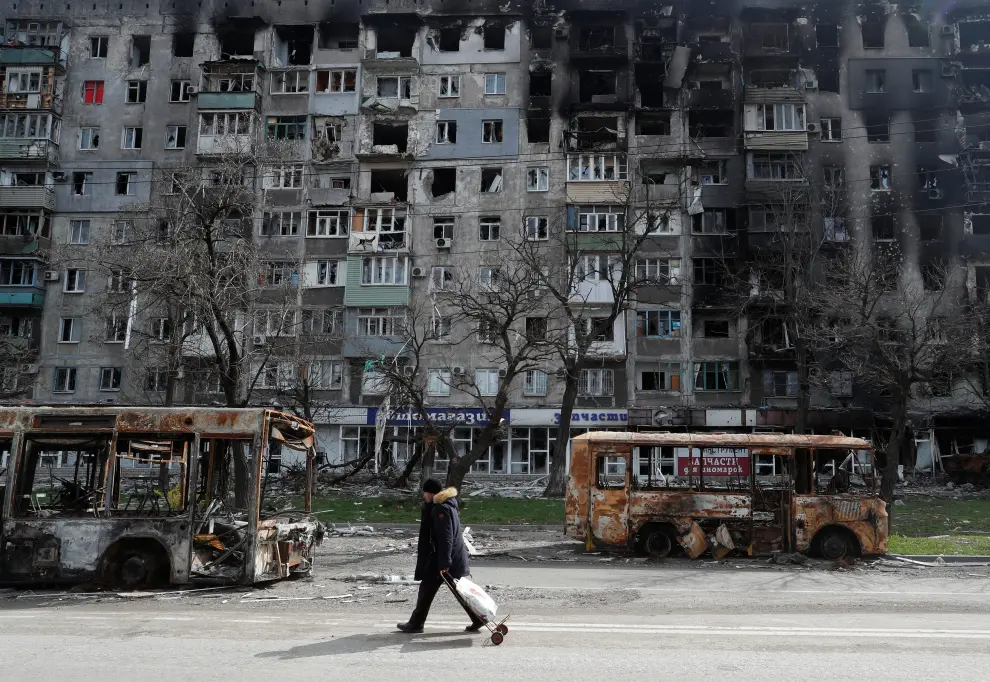 Local residents carry belongings past a building destroyed during Ukraine-Russia conflict in the southern port city of Mariupol, Ukraine April 19, 2022. REUTERS/Alexander Ermochenko UKRAINE-CRISIS/MARIUPOL