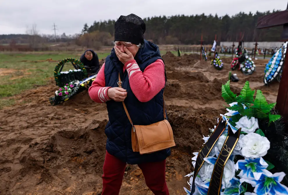 Natalia Maznichenko, 57, stands beside the coffin of her husband Vasyl Maznichenko, 61, who according to her was killed during Russian shelling on their building, as she mourns him before his burial, amid Russia's invasion of Ukraine, at the cemetery in Bucha, Kyiv region, Ukraine April 21, 2022. REUTERS/Zohra Bensemra UKRAINE-CRISIS/BUCHA