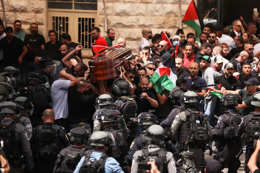 Family and friends carry the coffin of Al Jazeera reporter Shireen Abu Akleh, who was killed during an Israeli raid in Jenin in the occupied West Bank, as Israeli security forces stand guard, during her funeral in Jerusalem, May 13, 2022. REUTERS/Ammar Awad ISRAEL-PALESTINIANS/JOURNALIST