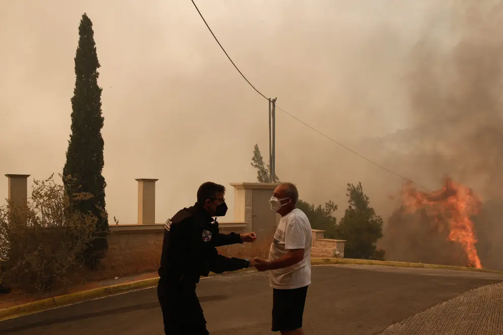 Athens (Greece), 04/06/2022.- A fireman gestures as he passes in front of a burning house during a wildfire in the suburb of Voula, south of Athens, Greece, 04 June 2022. Greek authorities ordered a limited evacuation in the coastal suburb of Voula, southern Athens, as strong winds fanning a raging fire have changed its direction, threatening residential area. (Incendio, Grecia, Atenas) EFE/EPA/YANNIS KOLESIDIS
 GREECE FIRE