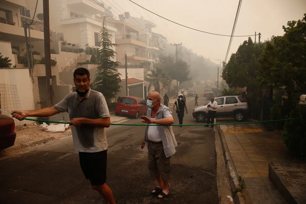 Athens (Greece), 04/06/2022.- A police officer tries to evacuate a resident during a wildfire in the suburb of Voula, south of Athens, Greece, 04 June 2022. Greek authorities ordered a limited evacuation in the coastal suburb of Voula, southern Athens, as strong winds fanning a raging fire have changed its direction, threatening residential area. (Incendio, Grecia, Atenas) EFE/EPA/YANNIS KOLESIDIS
 GREECE FIRE
