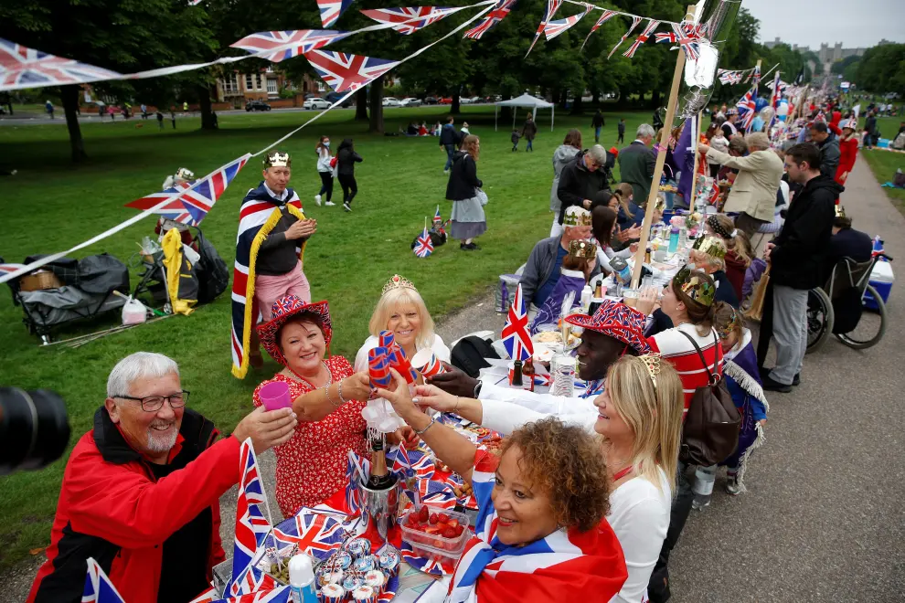 People dressed in outfits with a Union Jack theme and masks depicting Britain's Queen Elizabeth gather around a picnic table as they take part in the Big Jubilee Lunch on The Long Walk as part of celebrations marking the Platinum Jubilee of Britain's Queen Elizabeth, in Windsor, Britain, June 5, 2022. REUTERS/Peter Nicholls BRITAIN-ROYALS/PLATINUM-JUBILEE BIG LUNCH-WINDSOR