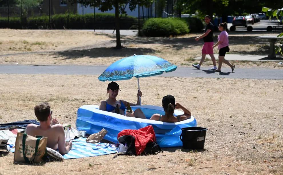 London (United Kingdom), 18/07/2022.- Friends sit in a kiddies paddling pool after a council parks vehicle filled their pool with water at a park in central London, Britain, 18 July 2022. The Met Office has issued a red extreme heat warning as the UK could have its hottest day on record this week, with temperatures forecast to hit up to 41 Celsius. (Reino Unido, Londres) EFE/EPA/ANDY RAIN
 BRITAIN WEATHER