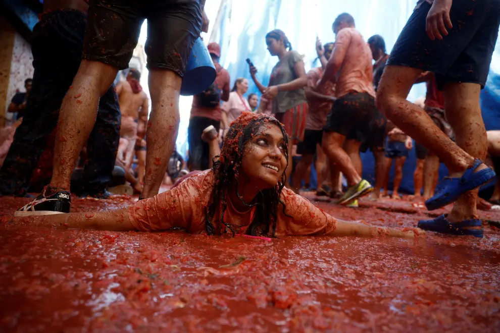 A reveler lies in tomato pulp during the annual "La Tomatina" food fight festival in Bunol, Spain August 31, 2022. REUTERS/Juan Medina SPAIN-CULTURE/TOMATO FIGHT