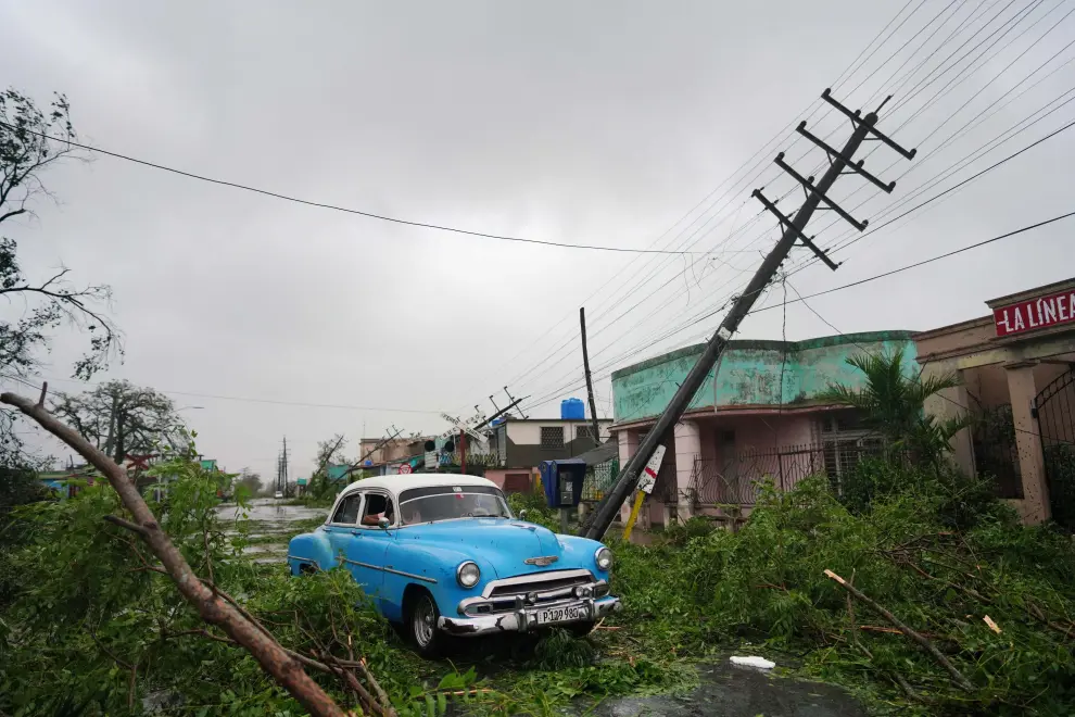 A vintage car passes by debris caused by the Hurricane Ian as it passed in Pinar del Rio, Cuba, September 27, 2022. REUTERS/Alexandre Meneghini      TPX IMAGES OF THE DAY STORM-IAN/CUBA