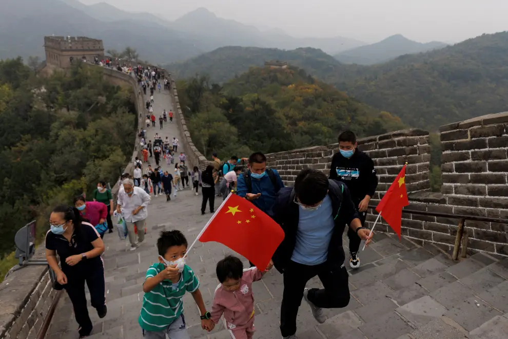 A man holds a Chinese flag as he poses for pictures on the Great Wall on National Day holiday following an outbreak of the coronavirus disease (COVID-19) in Beijing, China, October 1,  2022. REUTERS/Thomas Peter CHINA-ECONOMY/TRAVEL