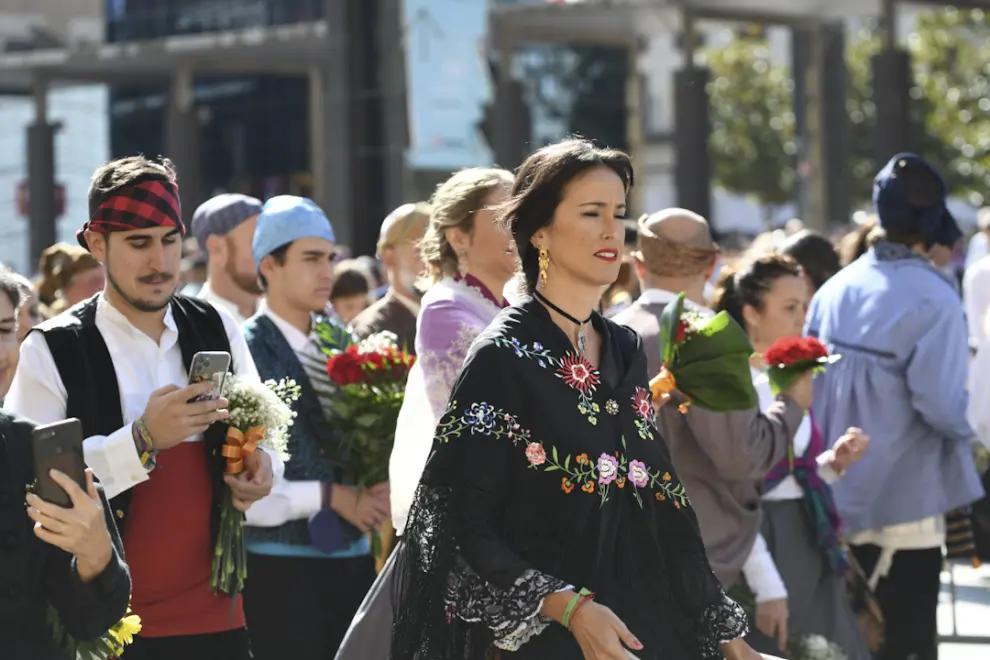 Llega la hora del vermú y la comida y los oferentes siguen pasando sin descanso por la plaza para dejar sus flores ante la Virgen