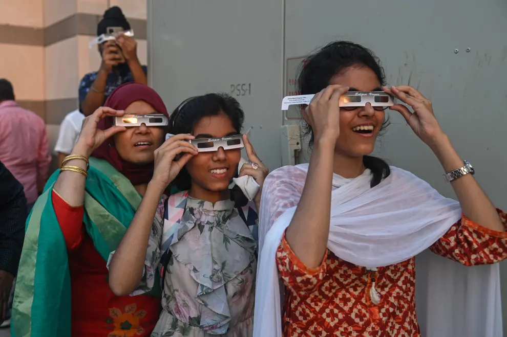 Mujeres con gafas especiales para ver el eclipse en Nueva Delhi, India