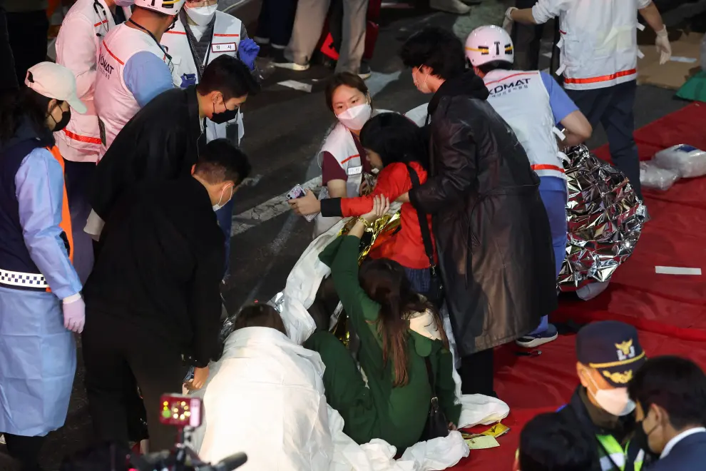 A man receives medical help from rescue team members at the scene where dozens of people were injured in a stampede during a Halloween festival in Seoul, South Korea, October 29, 2022. REUTERS/Kim Hong-ji SOUTHKOREA-STAMPEDE/