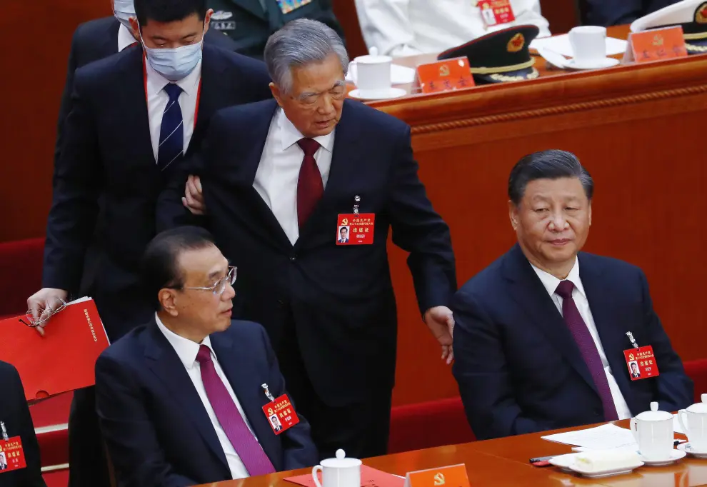 El expresidente chino Hu Jintao (c) es desalojado de la sala ante la impasible mirada del presiente Xi Jinping (d) y del primer ministro Li Keqiang (i), durante la ceremonia de clausura del del XX Congreso del Partido Comunista de China (PCCh), en Pekín, el 22 de octubre.