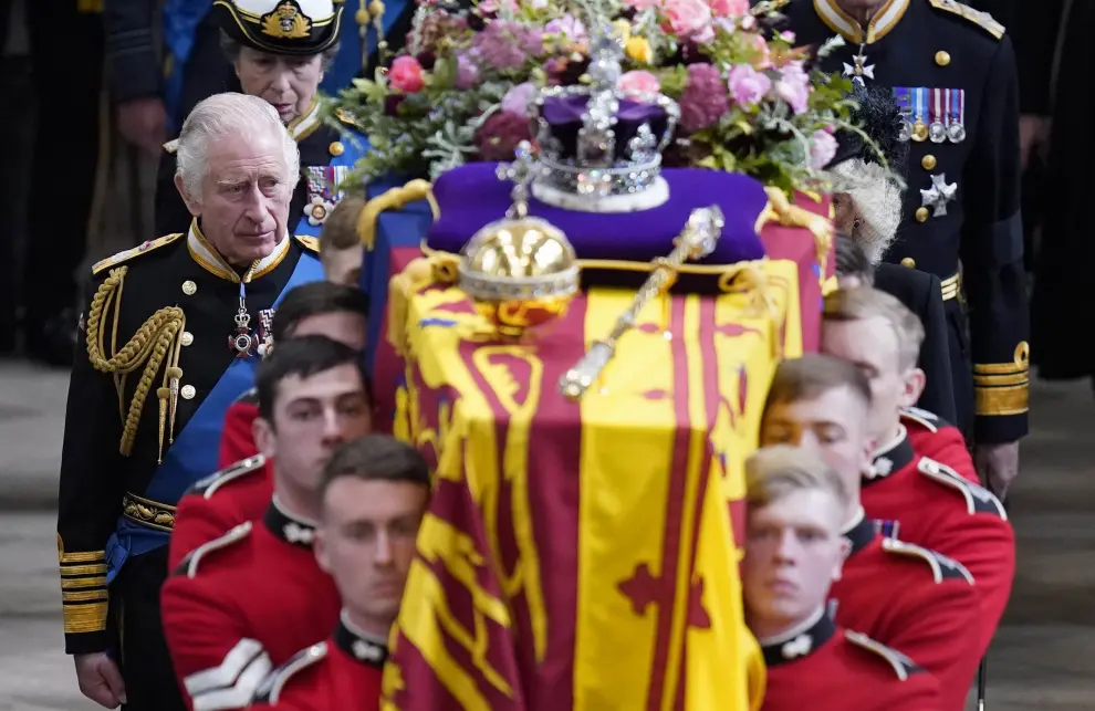 El rey Carlos III (izq.) y los miembros de la familia real siguen el ataúd de la reina Isabel II, envuelto en el estandarte real con la corona del estado imperial y el orbe y el cetro de los soberanos, mientras se lleva a cabo en la Abadía de Westminster después de su funeral de estado.