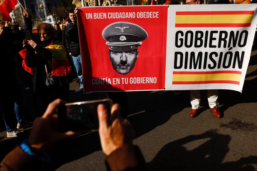 People hold a banner reading "A good citizen obeys. Trust your government" and with a depiction of Spanish Prime Minister Pedro Sanchez during a protest against his government, at Cibeles Square in Madrid, Spain, January 21, 2023. REUTERS/Susana Vera SPAIN-POLITICS/PROTEST