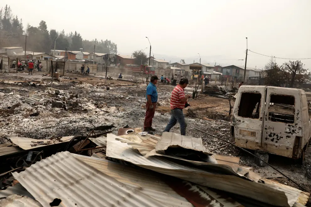 Local residents inspect the remains of burnt houses after a wildfire in Puren, near Temuco, Chile, February 4, 2023. REUTERS/Juan Gonzalez CHILE-FIRE/
