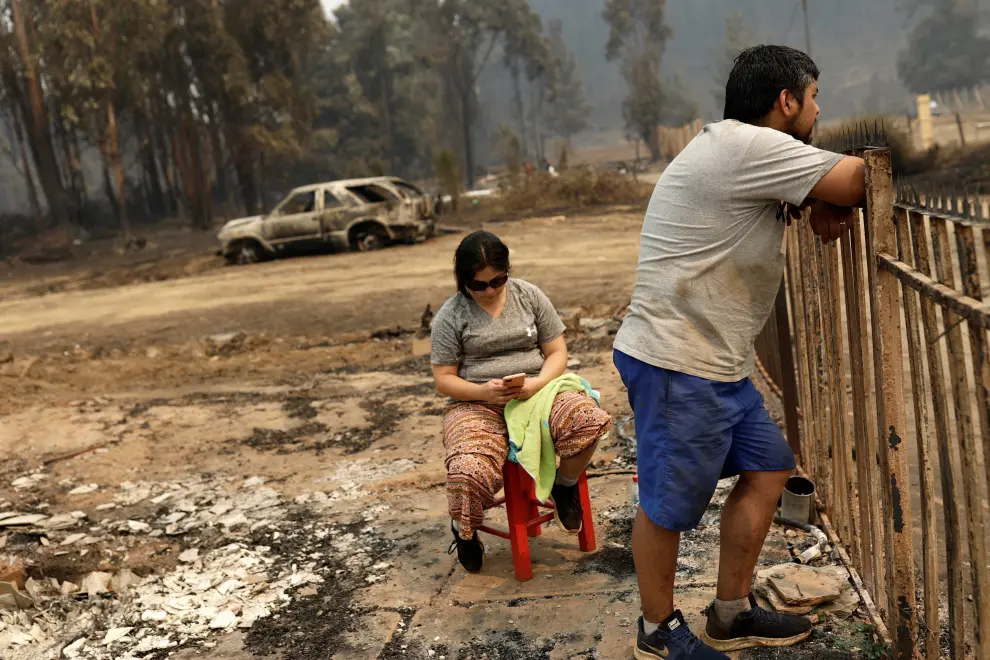 Local residents stand next to the remains of burnt houses after a wildfire in Puren, near Temuco, Chile, February 4, 2023. REUTERS/Juan Gonzalez CHILE-FIRE/