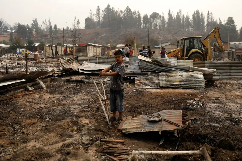 Local residents stay next to the remains of burnt houses after a wildfire in Puren, near Temuco, Chile, February 4, 2023. REUTERS/Juan Gonzalez CHILE-FIRE/