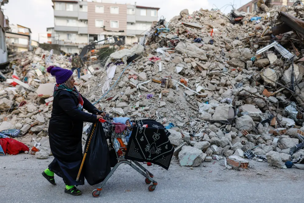 A woman pushes a shopping cart with a child, in the aftermath of a deadly earthquake, in Hatay, Turkey February 11, 2023. REUTERS/Kemal Aslan TURKEY-QUAKE/