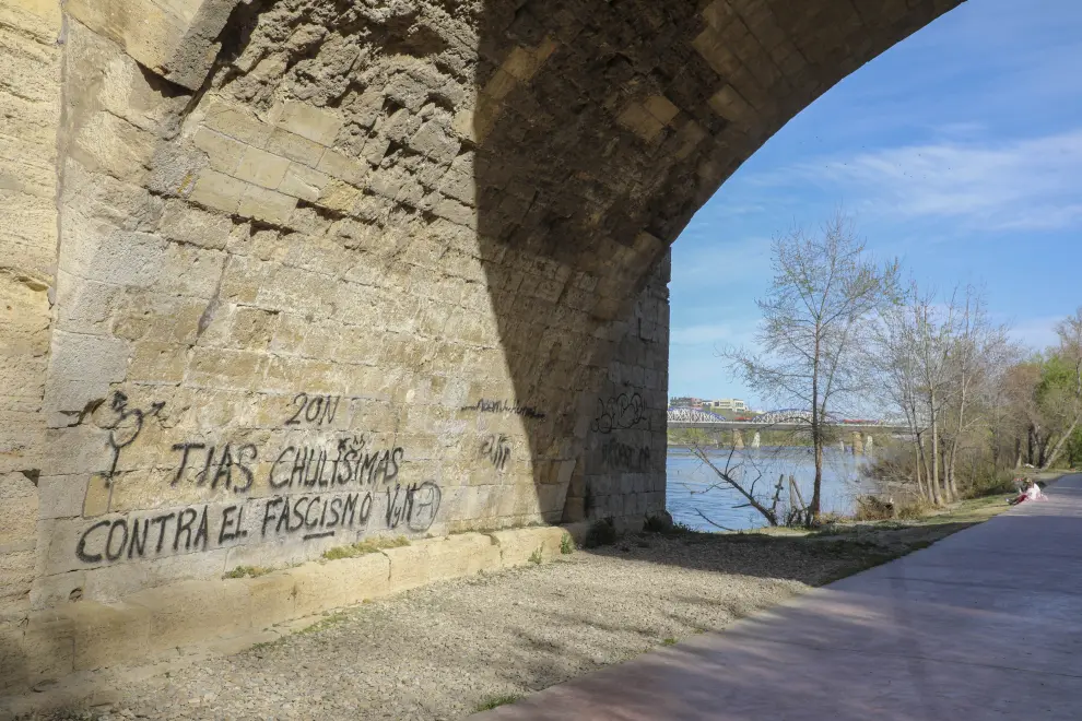 Los grafitis se ceban con comercios, viviendas y hasta monumentos como el puente de Piedra o la Seo.
