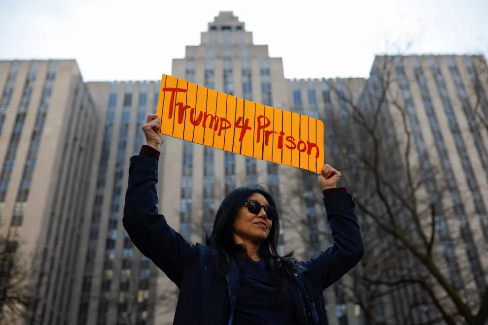 An anti-Trump protester holds a sign outside Manhattan Criminal Courthouse on the day of former U.S. President Donald Trump's planned court appearance after his indictment by a Manhattan grand jury following a probe into hush money paid to porn star Stormy Daniels, in New York City, U.S., April 4, 2023. REUTERS/Amanda Perobelli USA-TRUMP/