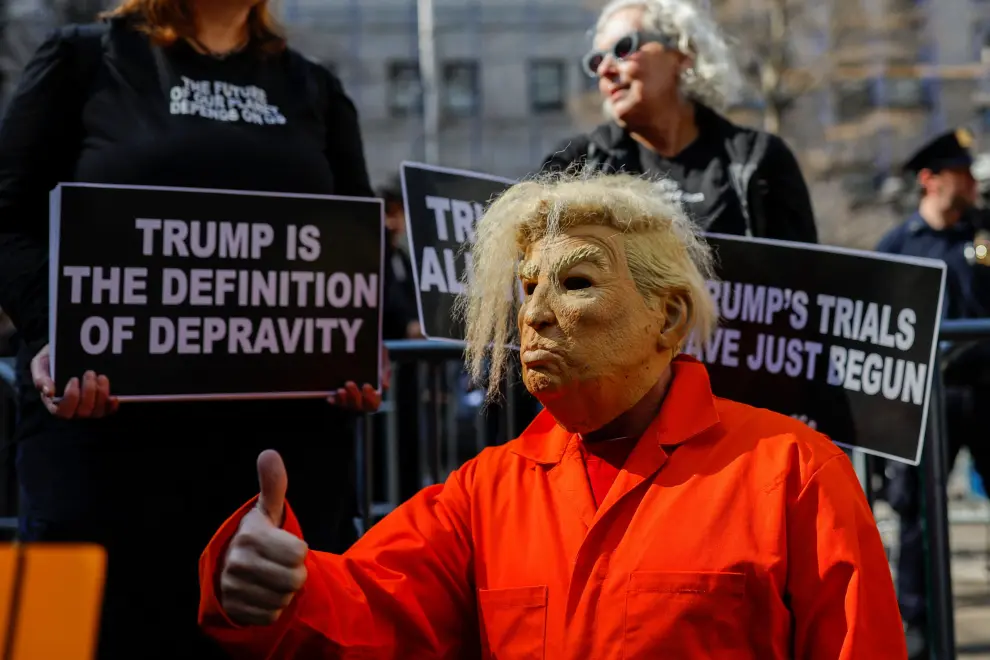 Anti-Trump protesters hold signs outside Manhattan Criminal Courthouse on the day of former U.S. President Donald Trump's planned court appearance after his indictment by a Manhattan grand jury following a probe into hush money paid to porn star Stormy Daniels, in New York City, U.S., April 4, 2023. REUTERS/Amanda Perobelli USA-TRUMP/