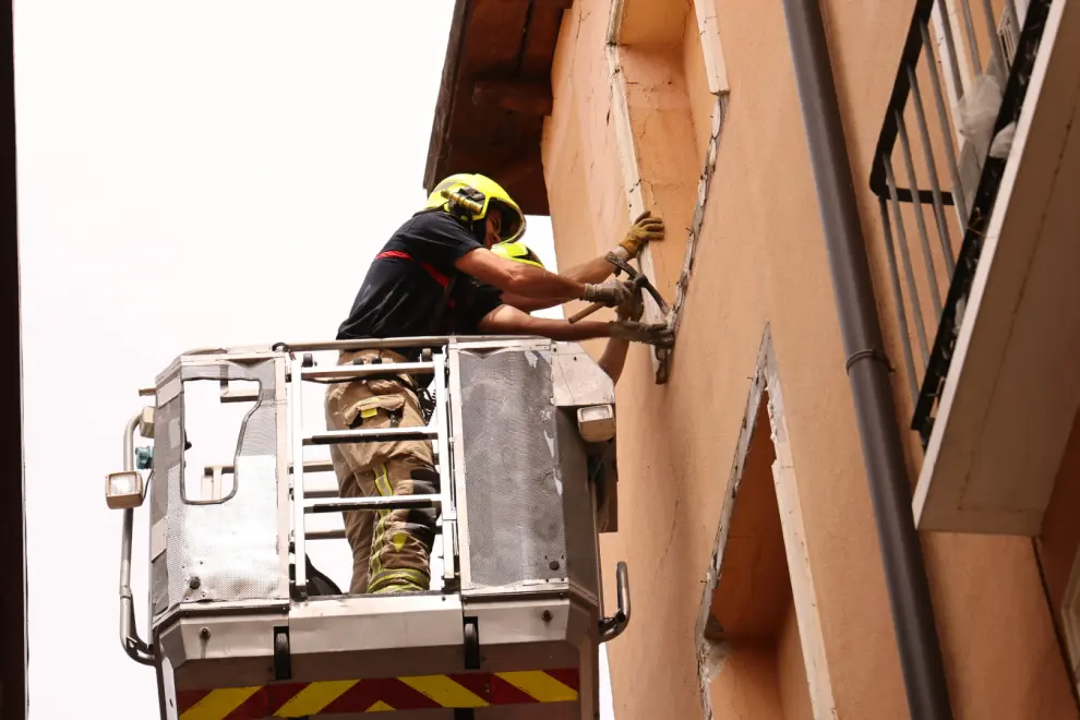 Tras la caída de un marco de yeso que ha herido a un hombre, los bomberos revisan y sanean uno a uno los elementos de la fachada de un edificio en la calle de Cinegio de Zaragoza.