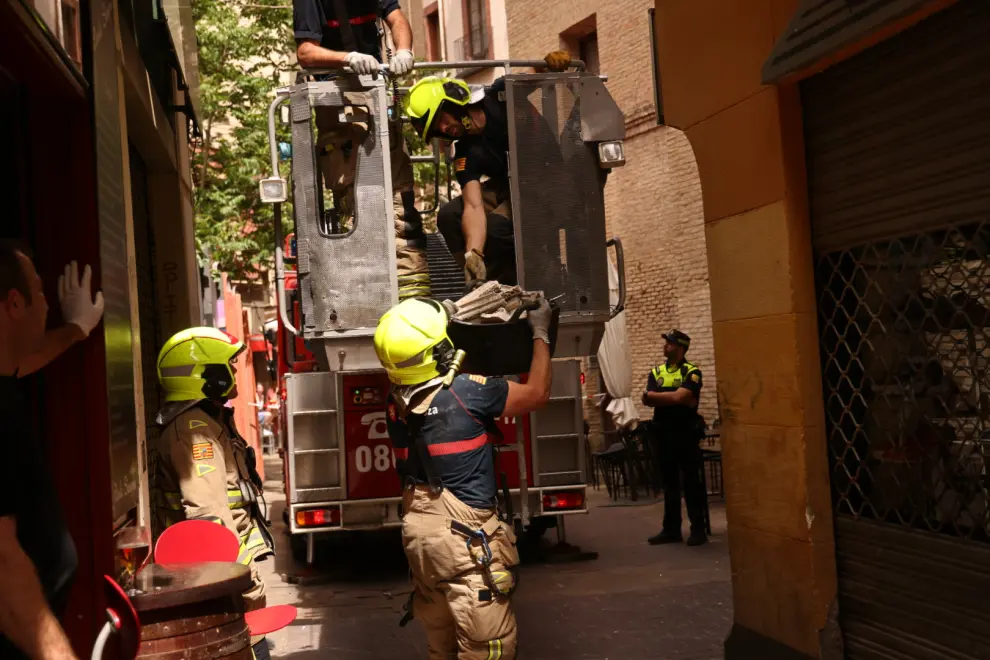 Tras la caída de un marco de yeso que ha herido a un hombre, los bomberos revisan y sanean uno a uno los elementos de la fachada de un edificio en la calle de Cinegio de Zaragoza.