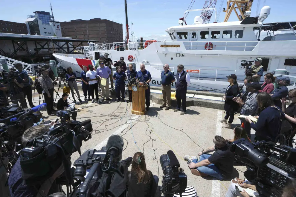U.S. Coast Guard Capt. Jamie Frederick, center at microphone, faces reporters during a news conference, Wednesday, June 21, 2023, at Coast Guard Base Boston, in Boston. The U.S. Coast Guard says sounds and banging noises have been heard from the search area for Titanic submersible. (AP Photo/Steven Senne)