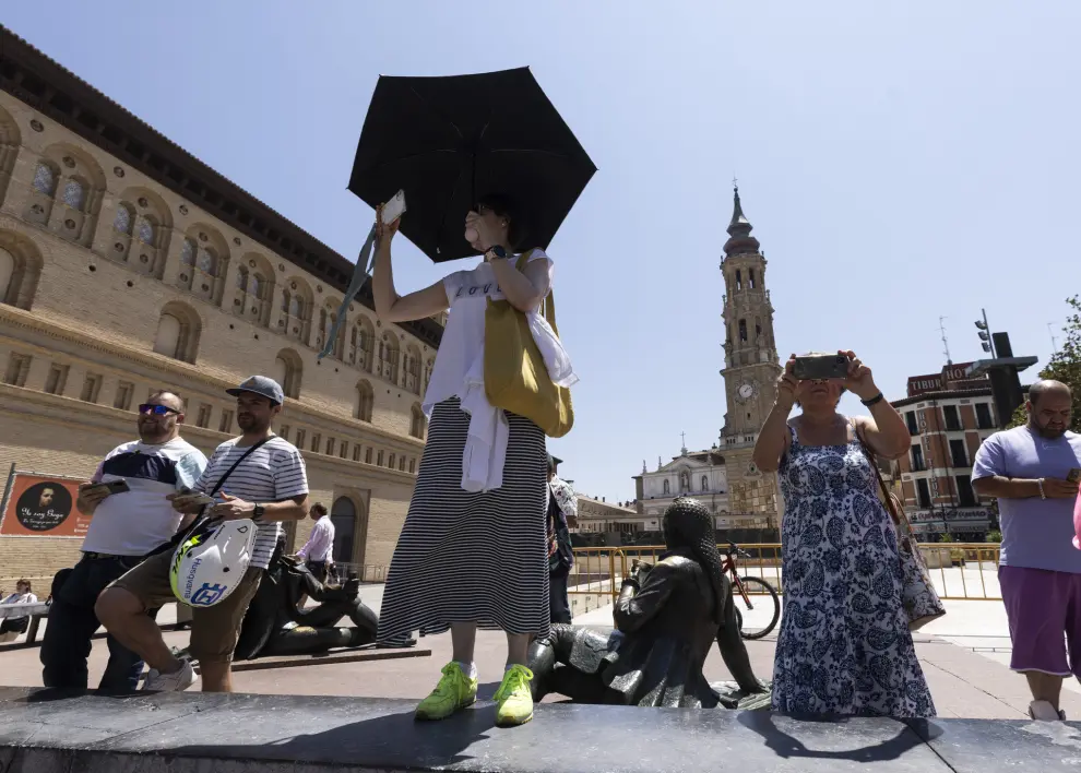 Primera ola de calor en Zaragoza. Gente con paraguas protegiéndose del sol en la plaza del Pilar.