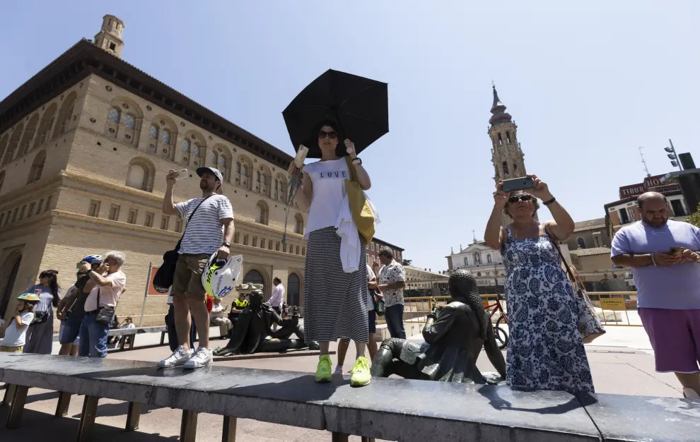 Gente con paraguas protegiéndose del sol en la plaza del Pilar.