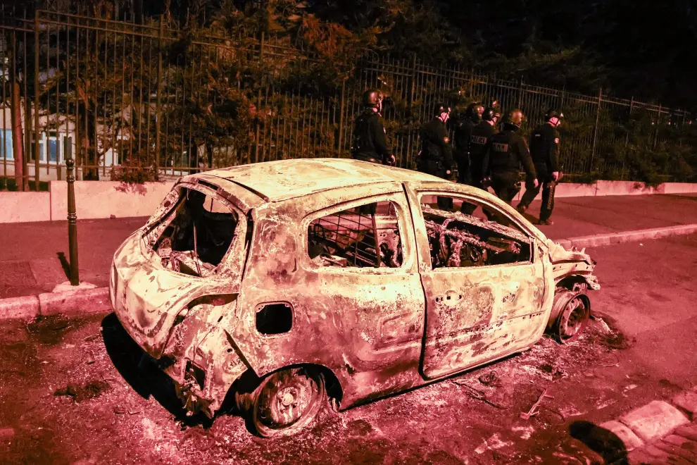 Nanterre (France), 30/06/2023.- Policemen walk next to a burned car destroyed during clashes between protesters and riot police in Nanterre, near Paris, France, France, early 01 July 2023. Violence broke out all over France after police fatally shot a 17-year-old teenager during a traffic stop in Nanterre on 27 June. (Protestas, Disturbios, Francia) EFE/EPA/MOHAMMED BADRA
 FRANCE RIOTS NANTERRE