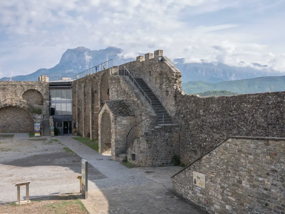 Muralla en el Castillo de Aínsa y oficina de turismo con el Pirineo de fondo