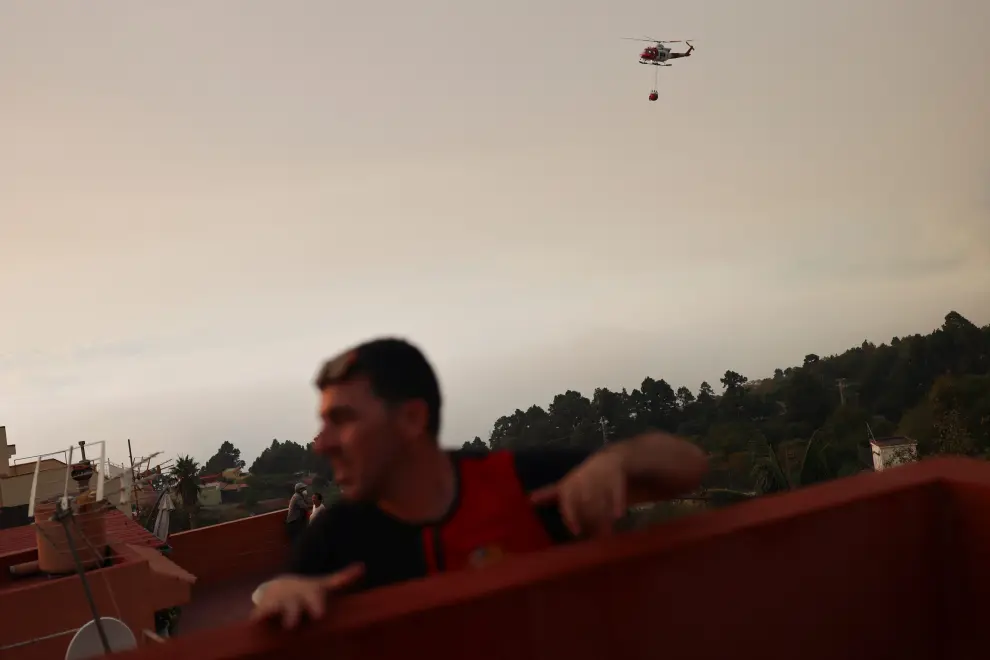 Neighbours look at a firefighting helicopter flying over Aguamansa, as wildfires rage out of control on the island of Tenerife, Canary Islands, Spain August 18, 2023. REUTERS/Nacho Doce EUROPE-WEATHER/SPAIN-WILDFIRES