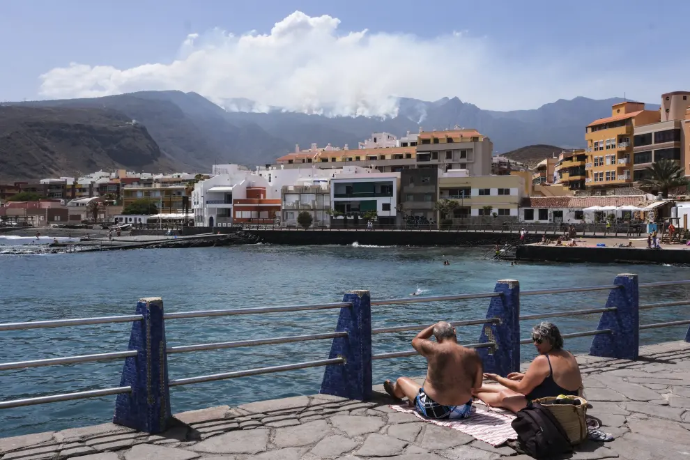 Varias personas disfrutaron este lunes de un rato de playa en el Puertito de Güímar, desde donde se puede ver el incendio que afecta a la isla de Tenerife desde hace siete días.