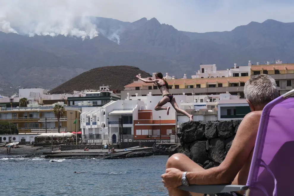 Varias personas disfrutaron este lunes de un rato de playa en el Puertito de Güímar, desde donde se puede ver el incendio que afecta a la isla de Tenerife desde hace siete días.