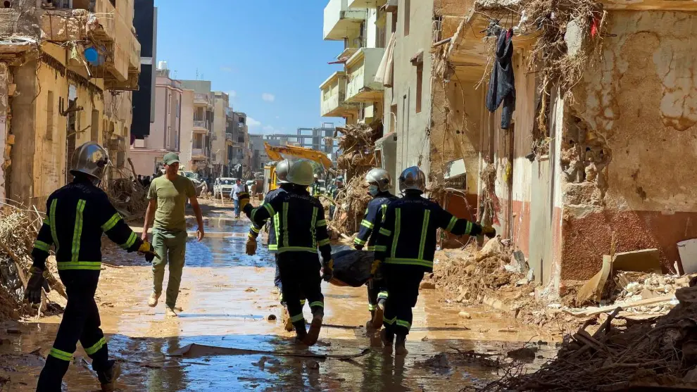 Members of the rescue teams from the Egyptian army carry a dead body as they walk in the mud between the destroyed buildings, after a powerful storm and heavy rainfall hit Libya, in Derna, Libya September 13, 2023. REUTERS/Ahmed Elumami