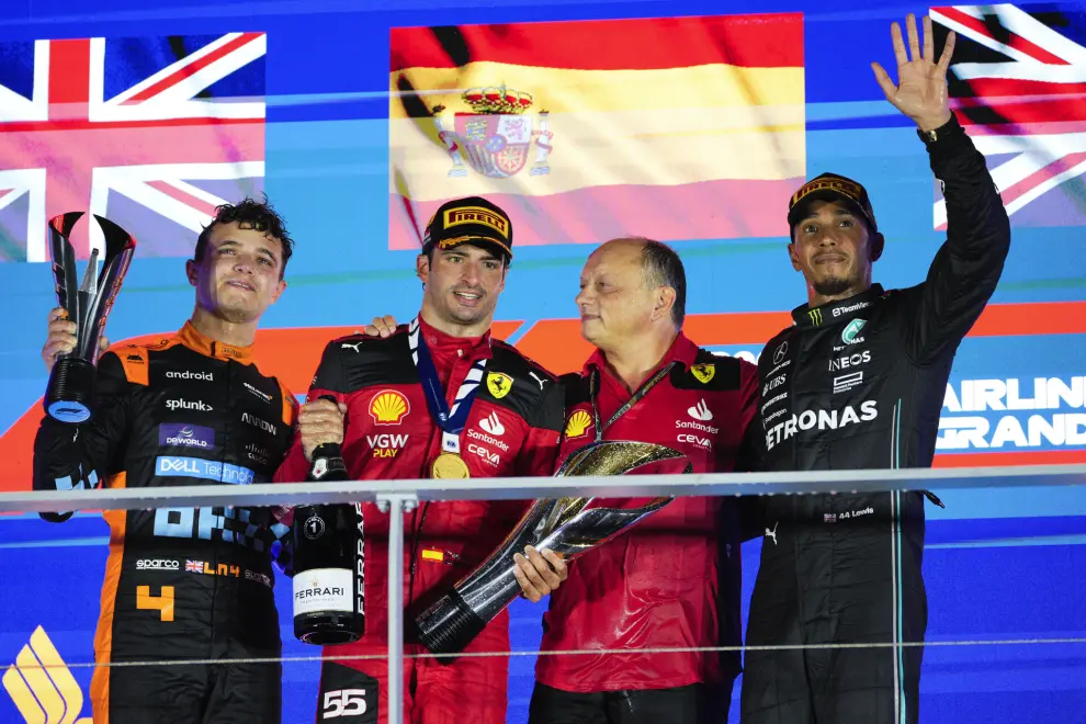Race winner Ferrari driver Carlos Sainz of Spain, second left, stands with second placed McLaren driver Lando Norris of Britain, left, and third placed Mercedes driver Lewis Hamilton of Britain, right, on the podium with a Ferrari teammate following the Singapore Formula One Grand Prix at the Marina Bay circuit, Singapore,Sunday, Sept. 17, 2023. (AP Photo/Vincent Thian)
