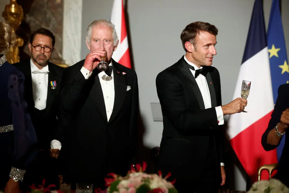 French President Emmanuel Macron raises his glass as he delivers a speech, while Britain's King Charles and Britain's Queen Camilla look on during a state banquet at the Palace of Versailles, west of Paris, on September 20, 2023, on the first day of a British royal state visit to France. DANIEL LEAL/Pool via REUTERS BRITAIN-ROYALS/FRANCE
