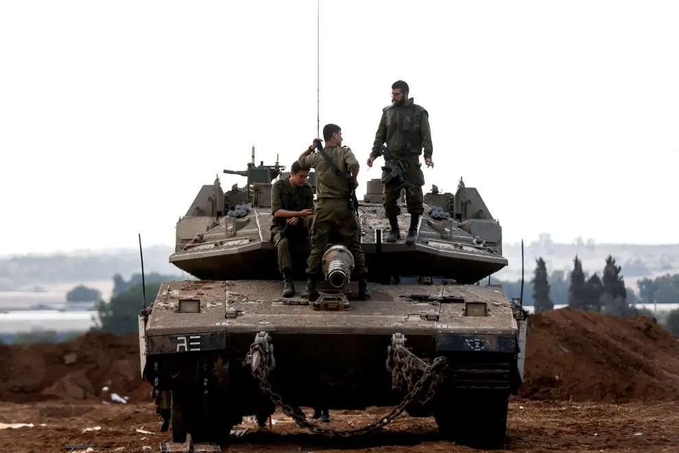 Israeli soldiers are silhouetted as they sit astride an Israeli tank near Israel's border with the Gaza Strip, in southern Israel October 15, 2023. REUTERS/Amir Cohen ISRAEL-PALESTINIANS/GAZA