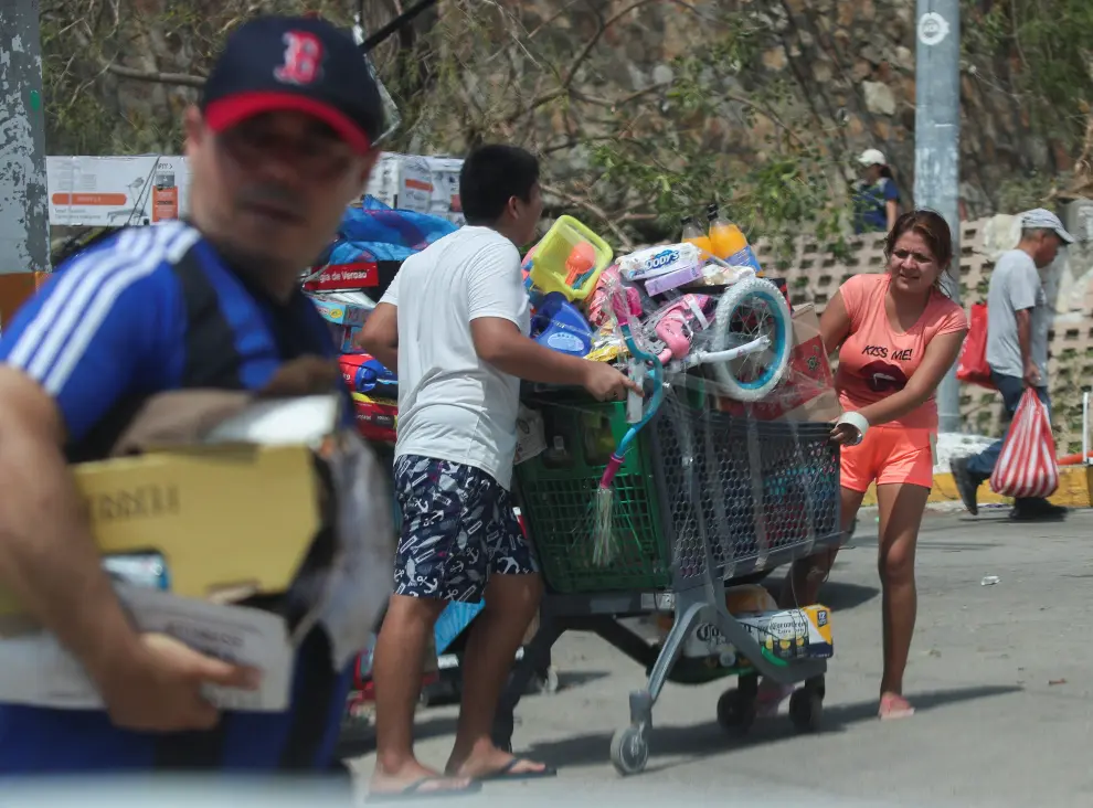 People leave with goods they took from a supermarket that had been broken into, in the aftermath of Hurricane Otis in Acapulco, Mexico, October 26, 2023. REUTERS/Henry Romero STORM-OTIS/