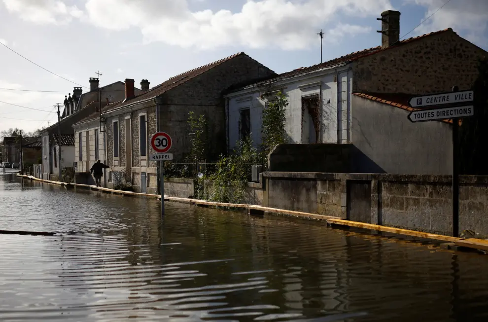 A man walks on a makeshift walkway in a flooded street as the Charente River overflows in Saintes after days of heavy rain causing flooding in western France, November 10, 2023. REUTERS/Stephane Mahe [[[REUTERS VOCENTO]]]